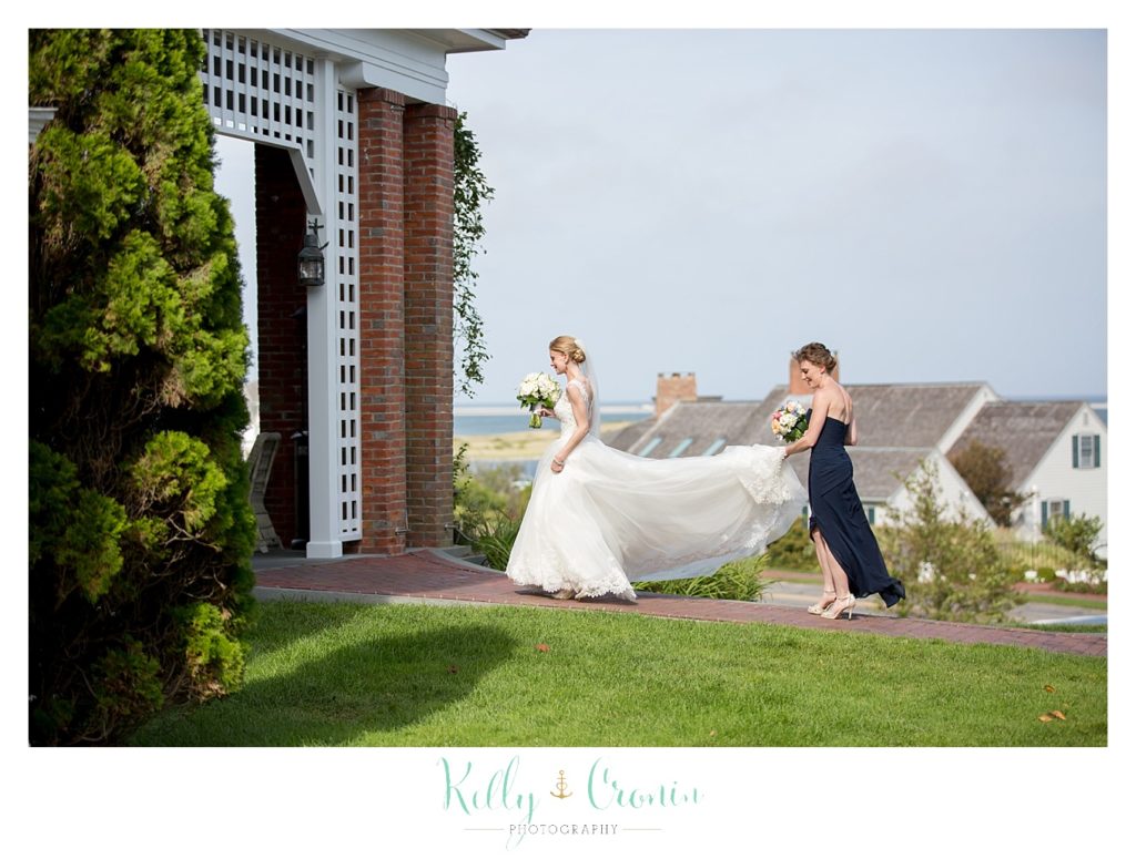 A bridesmaid carries the bride's train | Kelly Cronin Photography | Cape Cod Wedding Photographer