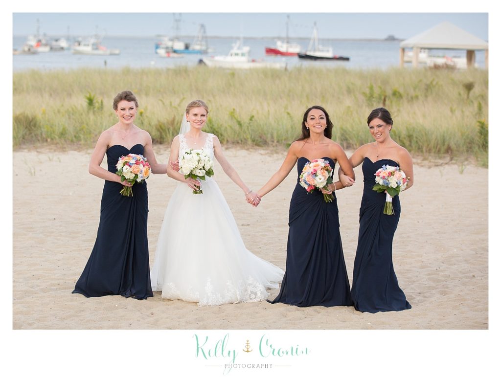 A bride holds hands with her bridesmaid | Kelly Cronin Photography | Cape Cod Wedding Photographer