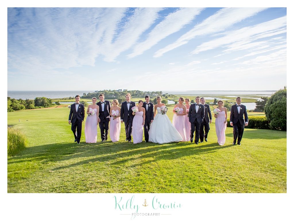 A wedding party stands in front of a blue sky  | Kelly Cronin Photography | Cape Cod Wedding Photographer