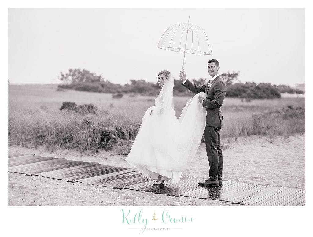 A groom holds his bride's dress up | Kelly Cronin Photography | Cape Cod Wedding Photographer