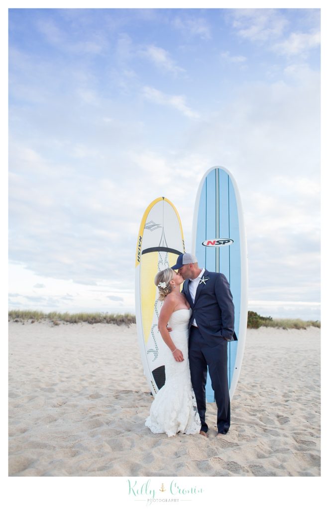 A couple kiss in front of surf boards | Kelly Cronin Photography | Cape Cod Wedding Photographer