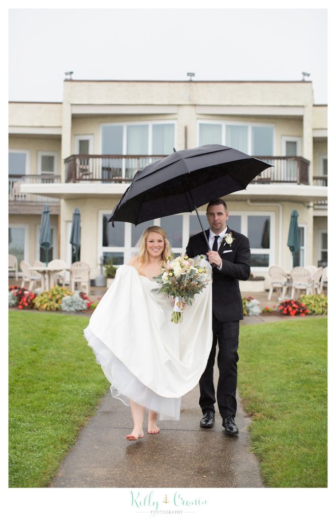 A couple walk under an umbrella  | Kelly Cronin Photography | Cape Cod Wedding Photographer