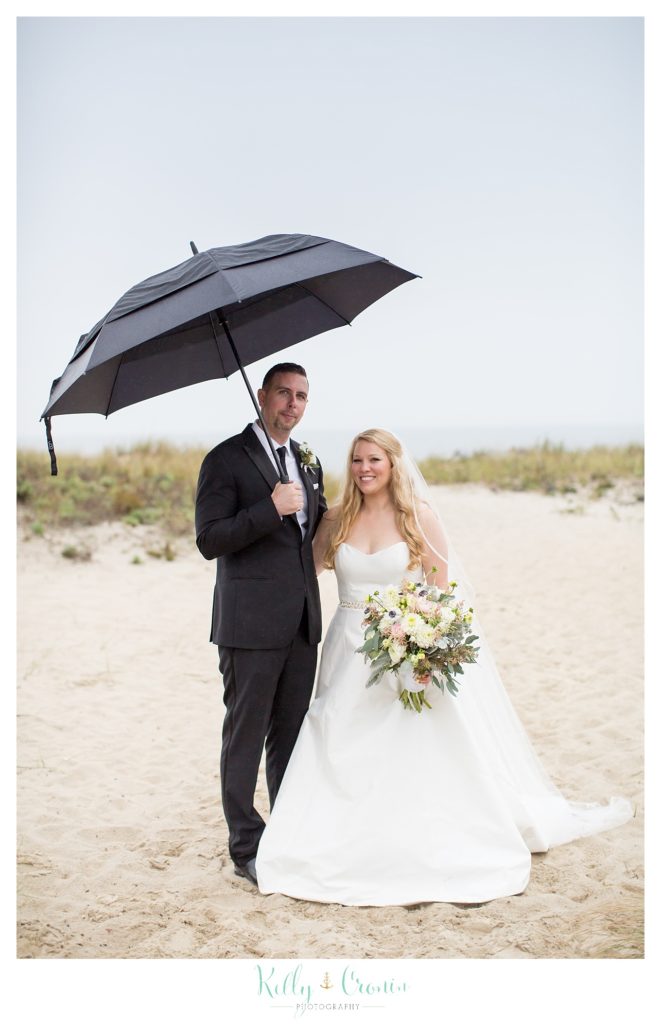 A man holds up an umbrella  | Kelly Cronin Photography | Cape Cod Wedding Photographer