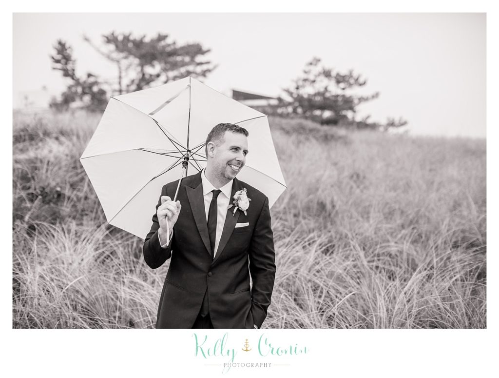 A groom holds an umbrella  | Kelly Cronin Photography | Cape Cod Wedding Photographer