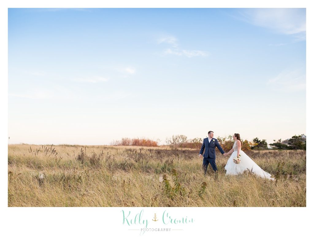 A couple walks through a field | Kelly Cronin Photography | Cape Cod Wedding Photographer