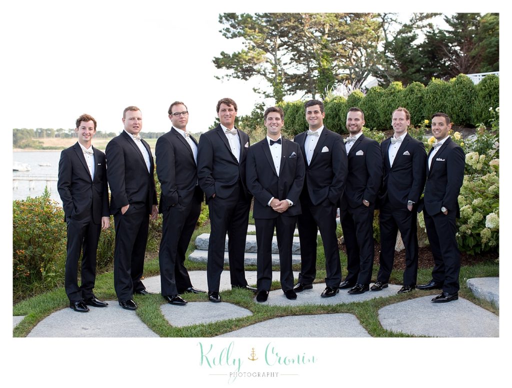 A groom stands with his groomsmen, ready to give his bride a Romance in Cape Cod. | Captured by Kelly Cronin Photography