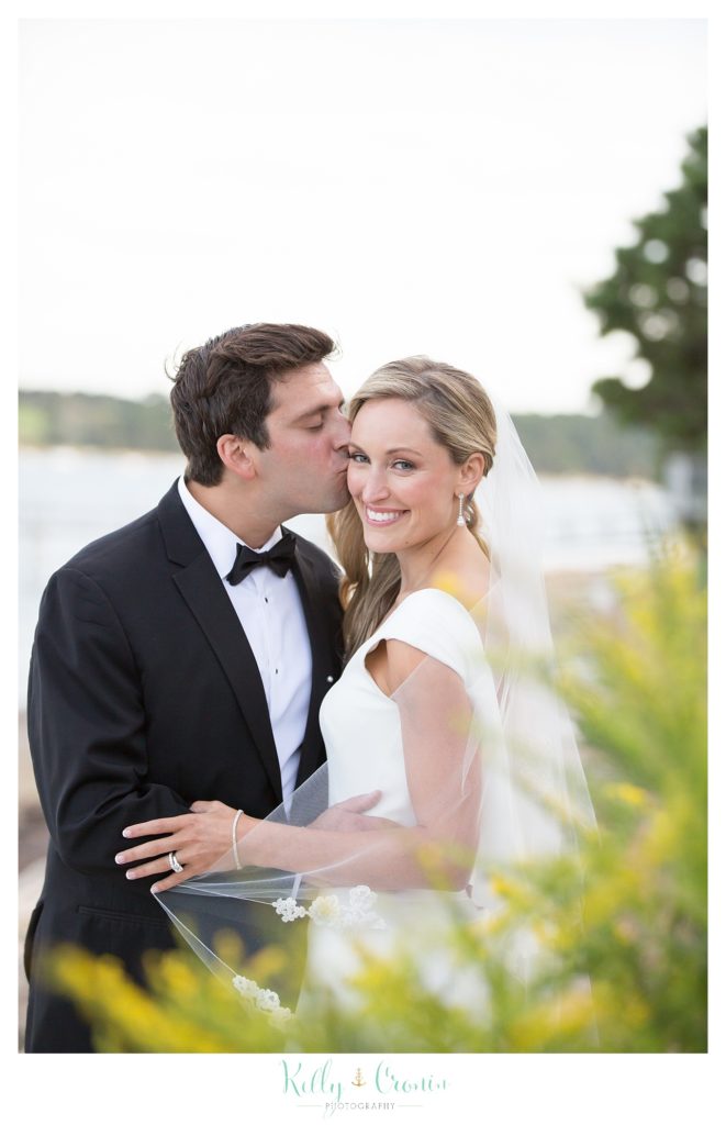 A groom kisses his bride, creating Romance in Cape Cod. | Captured by Kelly Cronin Photography