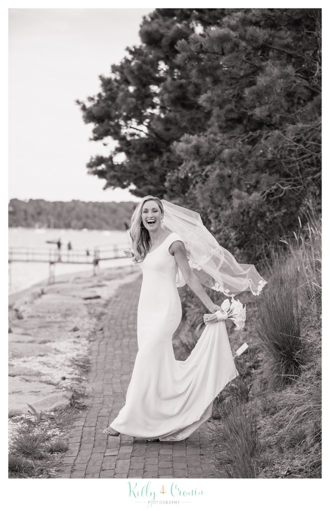 A bride holds her dress in celebration of Romance in Cape Cod. | Captured by Kelly Cronin Photography