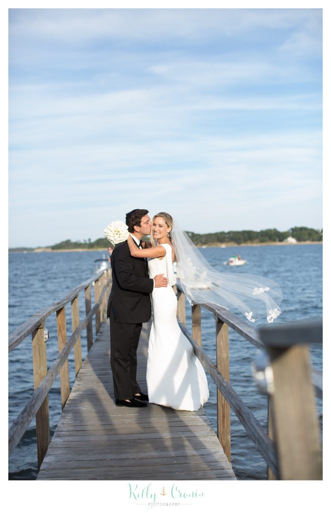 A groom kisses his wife, celebrating their Romance in Cape Cod. | Captured by Kelly Cronin Photography