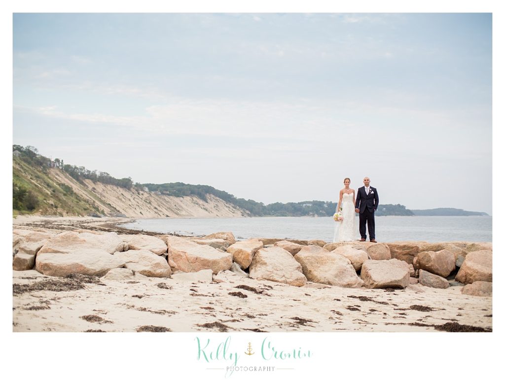 A newlywed couple walk along the shore, wedding held at the White Cliffs Country club and captured by Kelly Cronin Photography