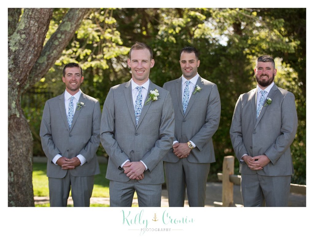 A groom and his groomsmen stand outside of The Dennis Inn, captured by Kelly Cronin Photography