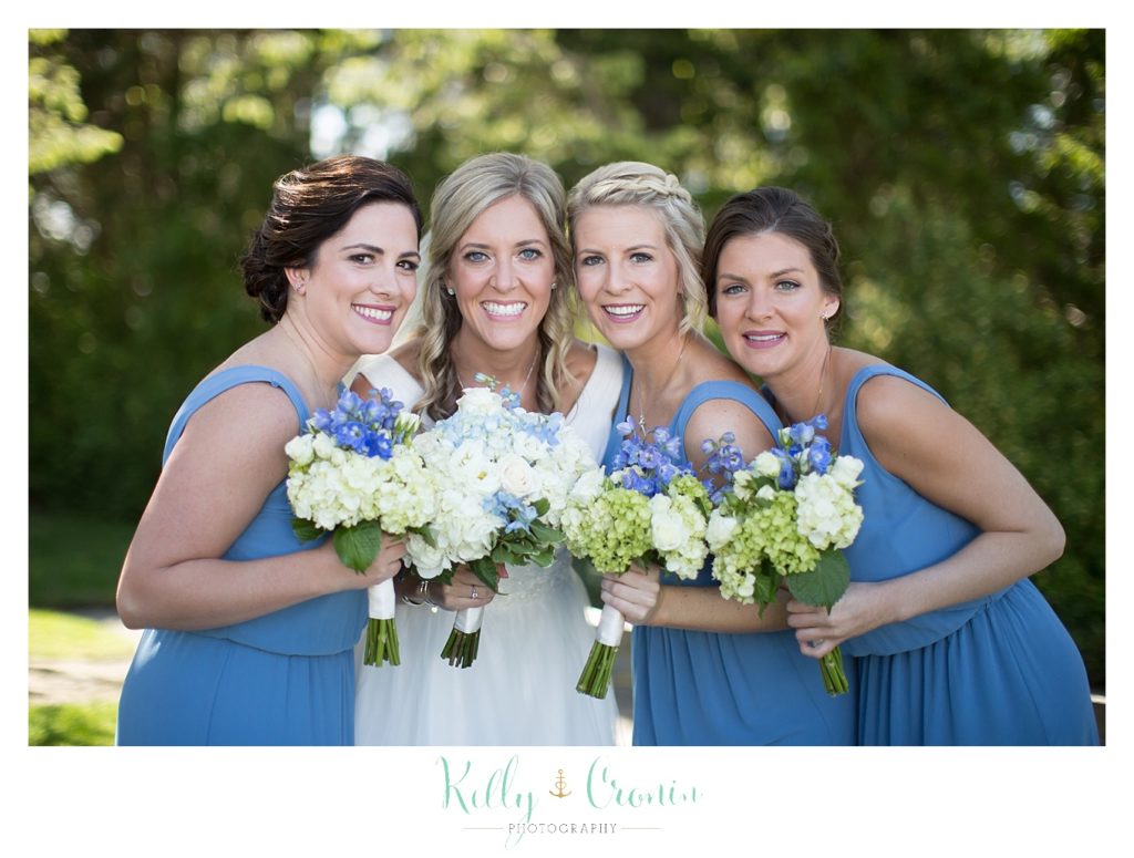 A bride smiles with her bridal party outside of The Dennis Inn, captured by Kelly Cronin Photography
