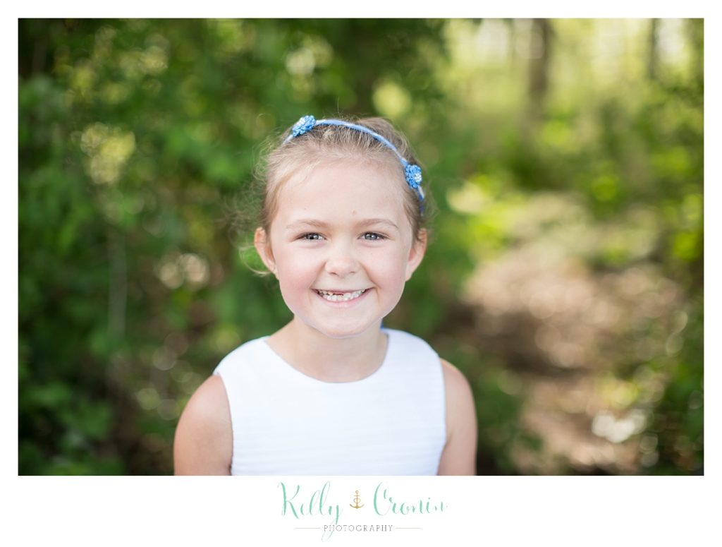 The flower girl smiles on the lawn of The Dennis Inn, captured by Kelly Cronin Photography