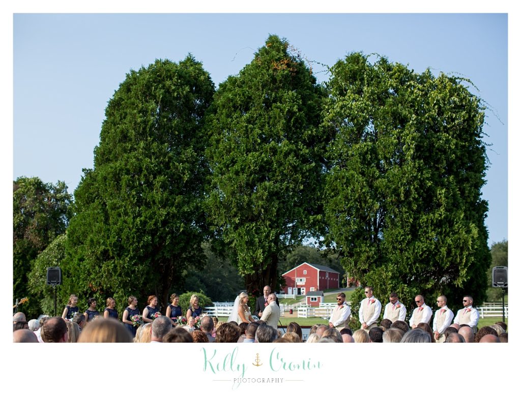 A wedding ceremony is held in front of a barn | Kelly Cronin Photography | CJ's Ranch