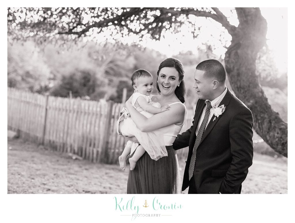 A couple hold the flower girl, this was a Mooncussers Tavern Reception, captured by Kelly Cronin Photography
