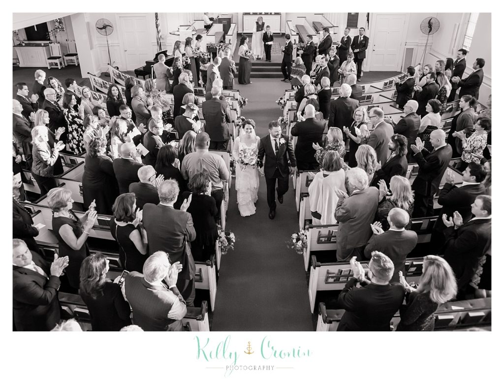 A couple walk down the aisle after their wedding, this was a Mooncussers Tavern Reception, captured by Kelly Cronin Photography