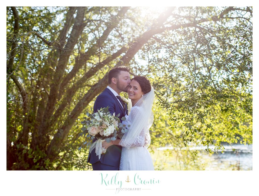 A groom kisses his bride, this was a Mooncussers Tavern Reception, captured by Kelly Cronin Photography