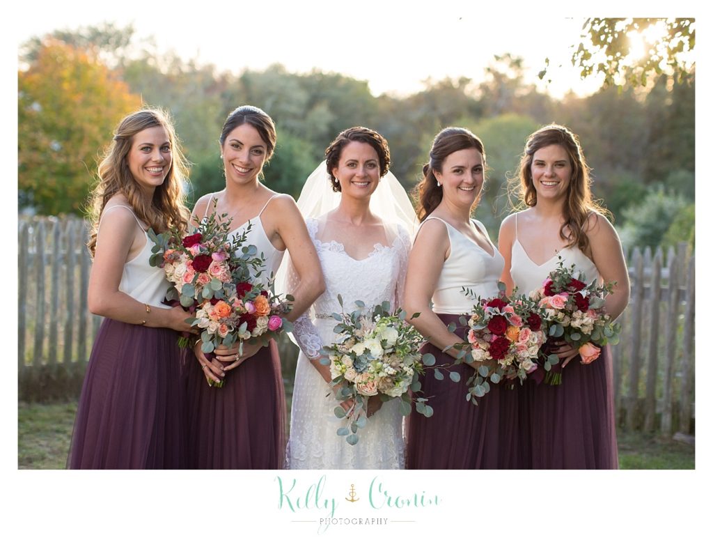 A bride stands with her bridal party, this was a Mooncussers Tavern Reception, captured by Kelly Cronin Photography