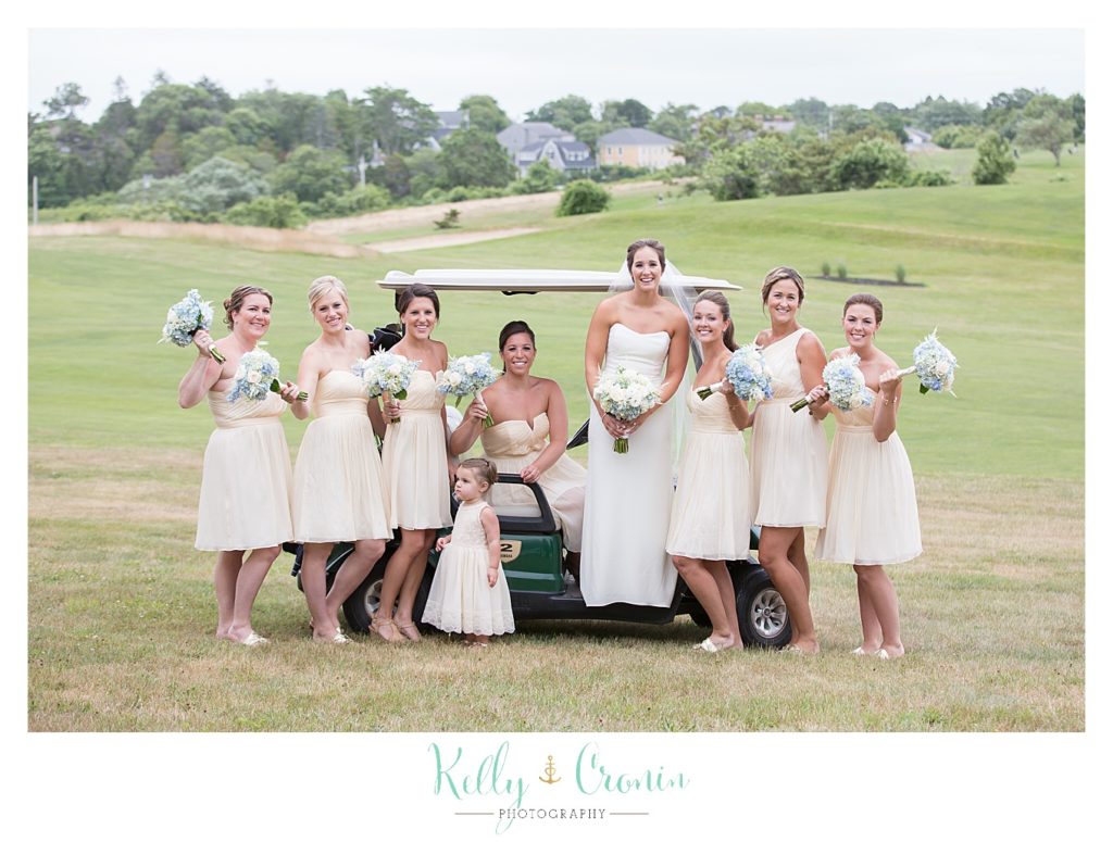 A bridal party pose in front of a golf cart | Kelly Cronin Photography | Lighthouse Beach