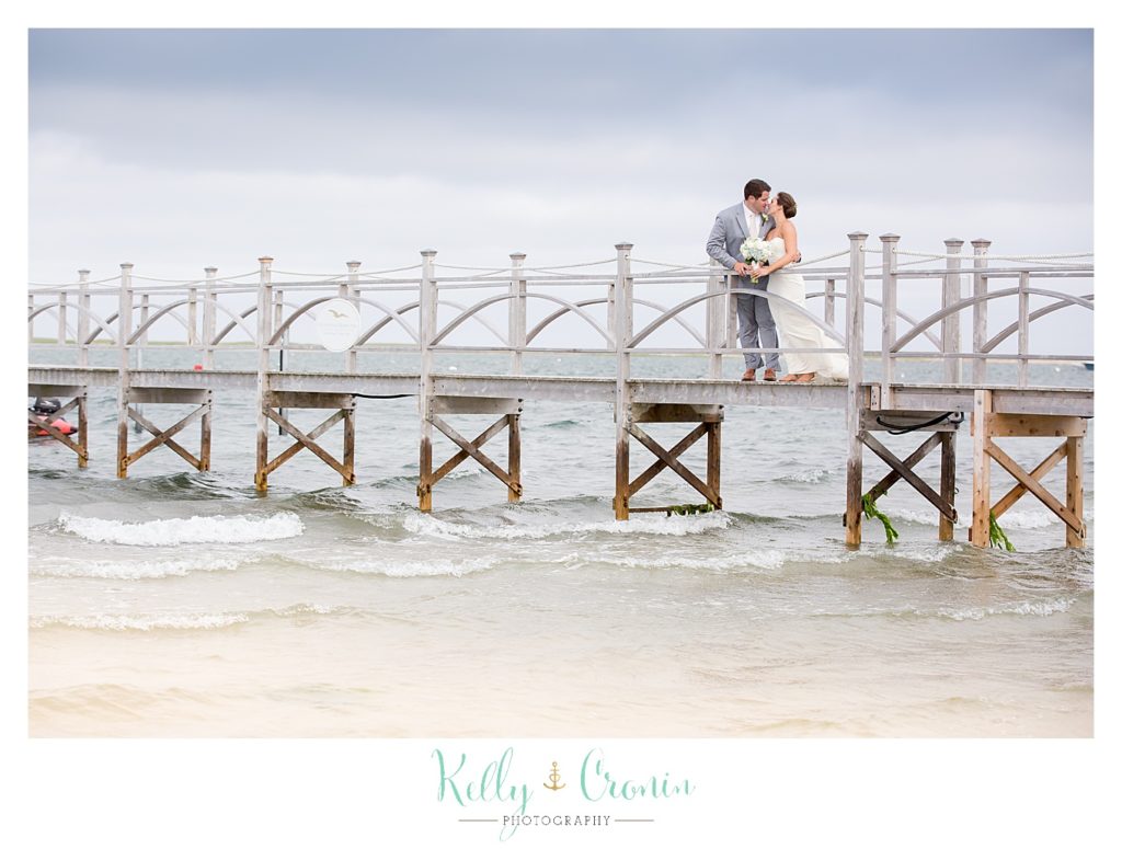 A bride kisses her groom on a pier | Kelly Cronin Photography | Lighthouse Beach