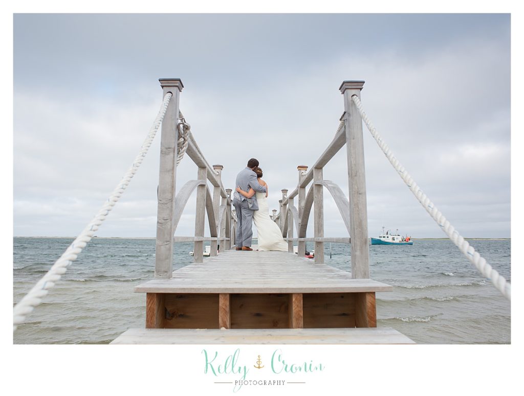 A newly married couple kiss on a pier | Kelly Cronin Photography | Lighthouse Beach