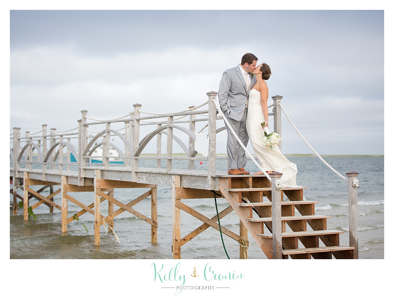 A newlywed couple kiss on a pier | Kelly Cronin Photography | Lighthouse Beach