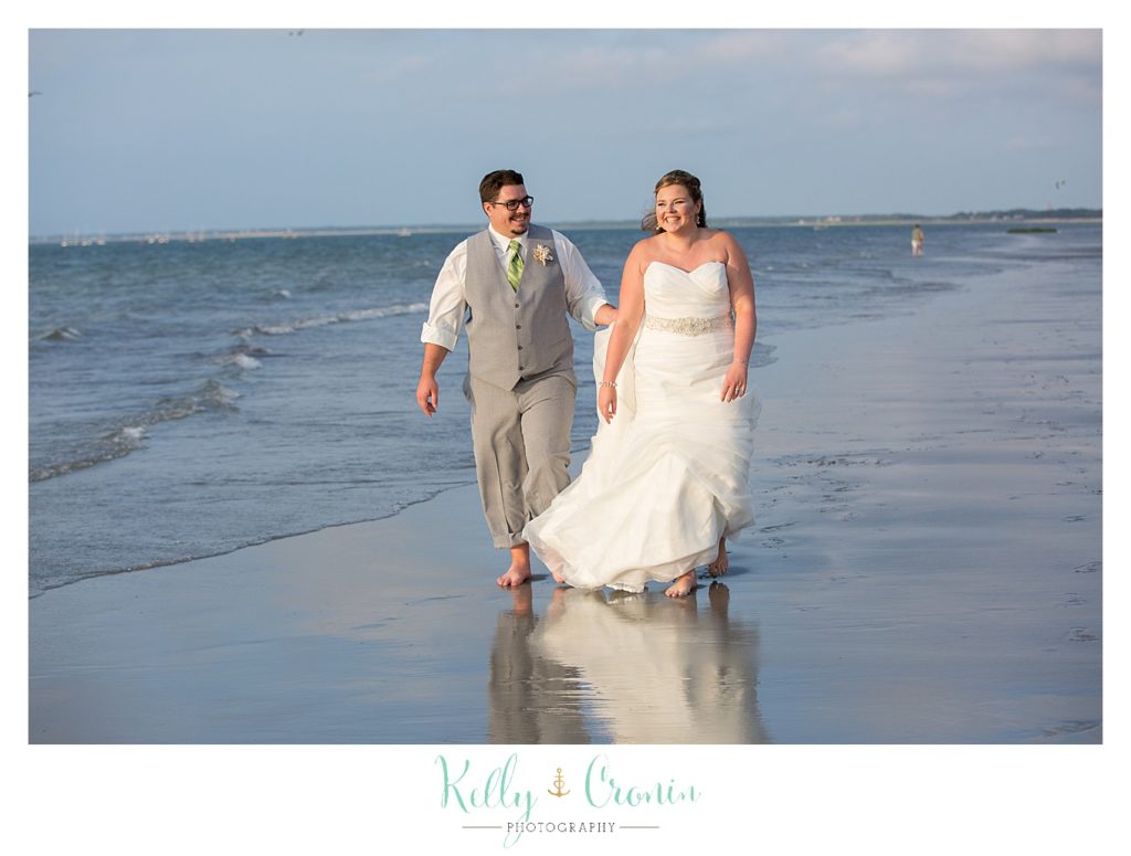 A bride takes a walk with her groom on the beach | Kelly Cronin Photography | Ocean Edge Resort and Golf Club