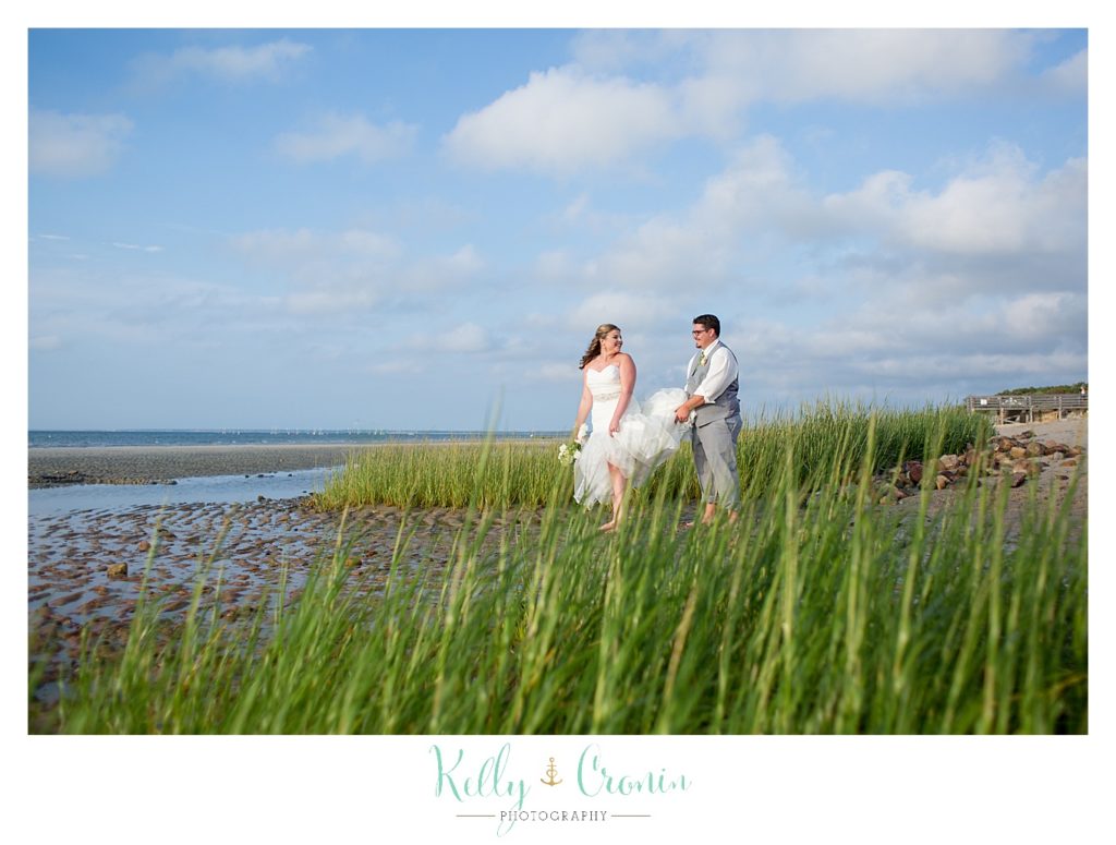 A groom carries his bride's dress | Kelly Cronin Photography | Ocean Edge Resort and Golf Club