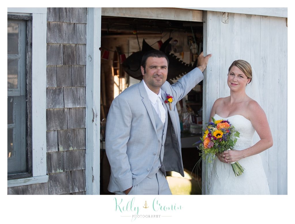 A groom rests his hand against a wall  | Kelly Cronin Photography | Oyster River Landing