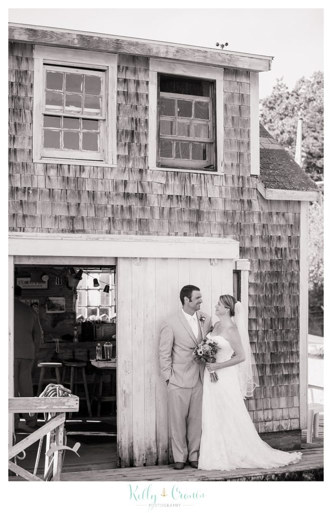 A couple stand in front of a rustic building  | Kelly Cronin Photography | Oyster River Landing