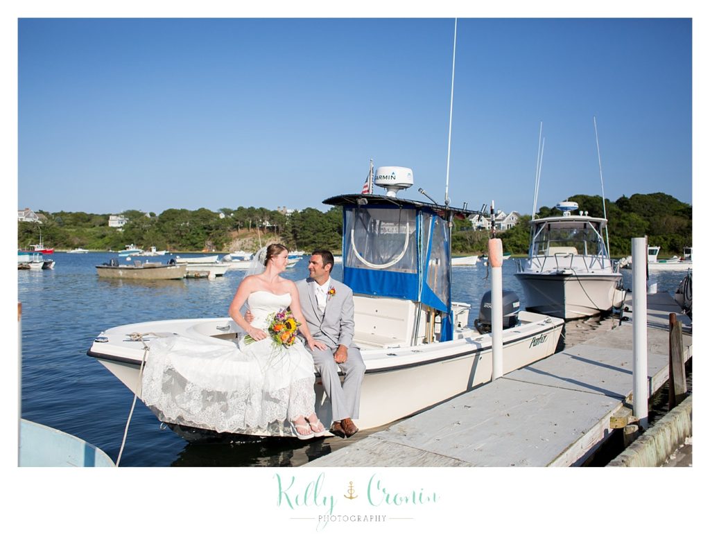 A bride and groom sit on a boat  | Kelly Cronin Photography | Oyster River Landing
