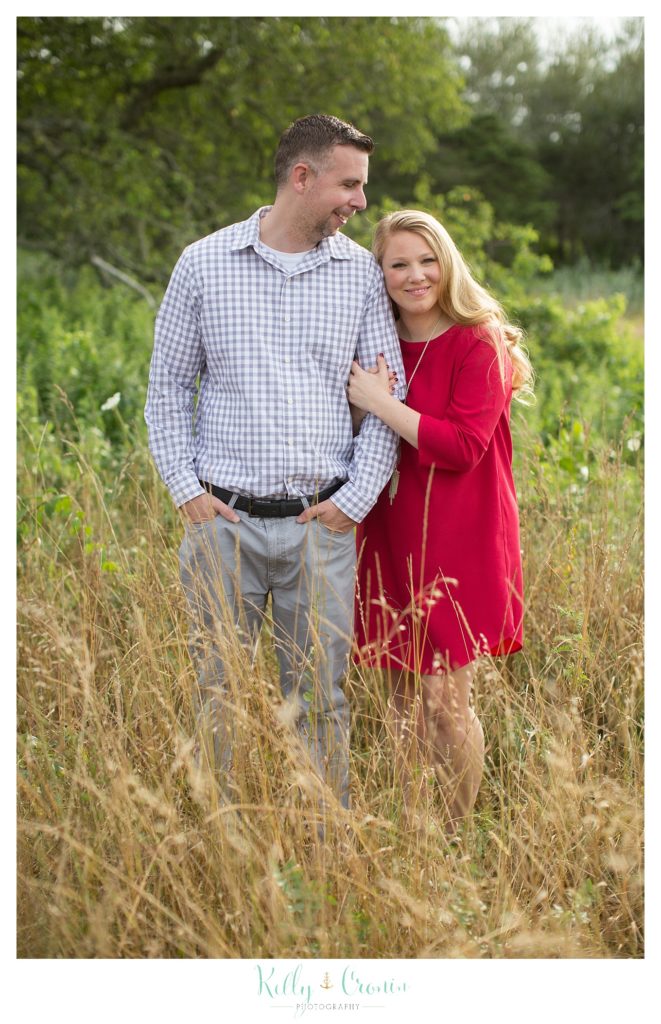 A woman hangs on to her fiance's arm  | Kelly Cronin Photography | Outdoor Engagement Session