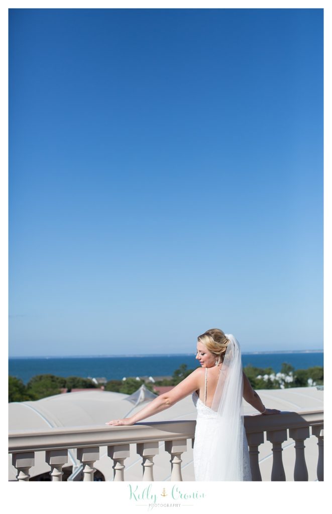 A bride looks over a balcony | Kelly Cronin Photography | Resort Wedding in Cape Cod