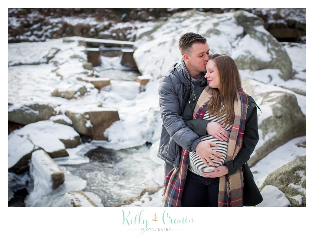 A man wraps his arms around his wife  | Kelly Cronin Photography | Cape Cod Maternity Photographer