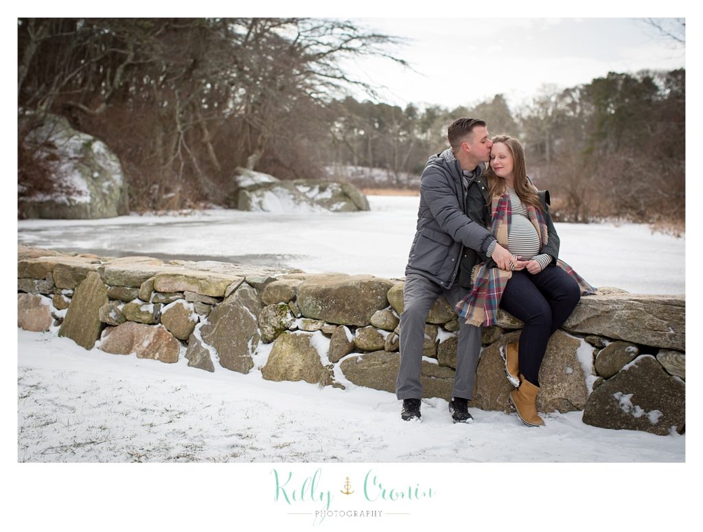 A man sits behind his pregnant wife  | Kelly Cronin Photography | Cape Cod Maternity Photographer