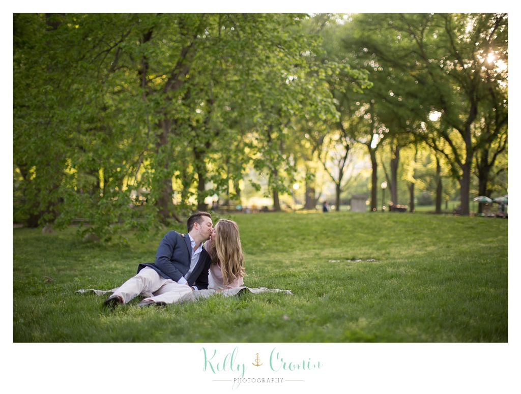 An engaged couple sit in the grass together  | Kelly Cronin Photography | NYC Engagement Shoot