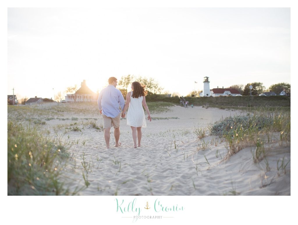 A Cape Cod engagement photographer captures a couple walking. 