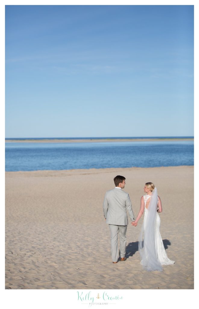 A newlywed couple take a walk on the beach