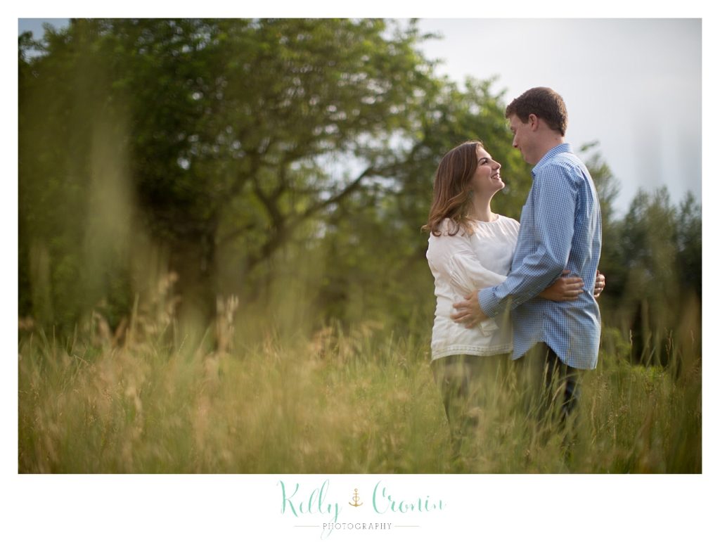 A couple embrace surrounded by the grass in Thompson's Field, captured by Kelly Cronin Photography. 