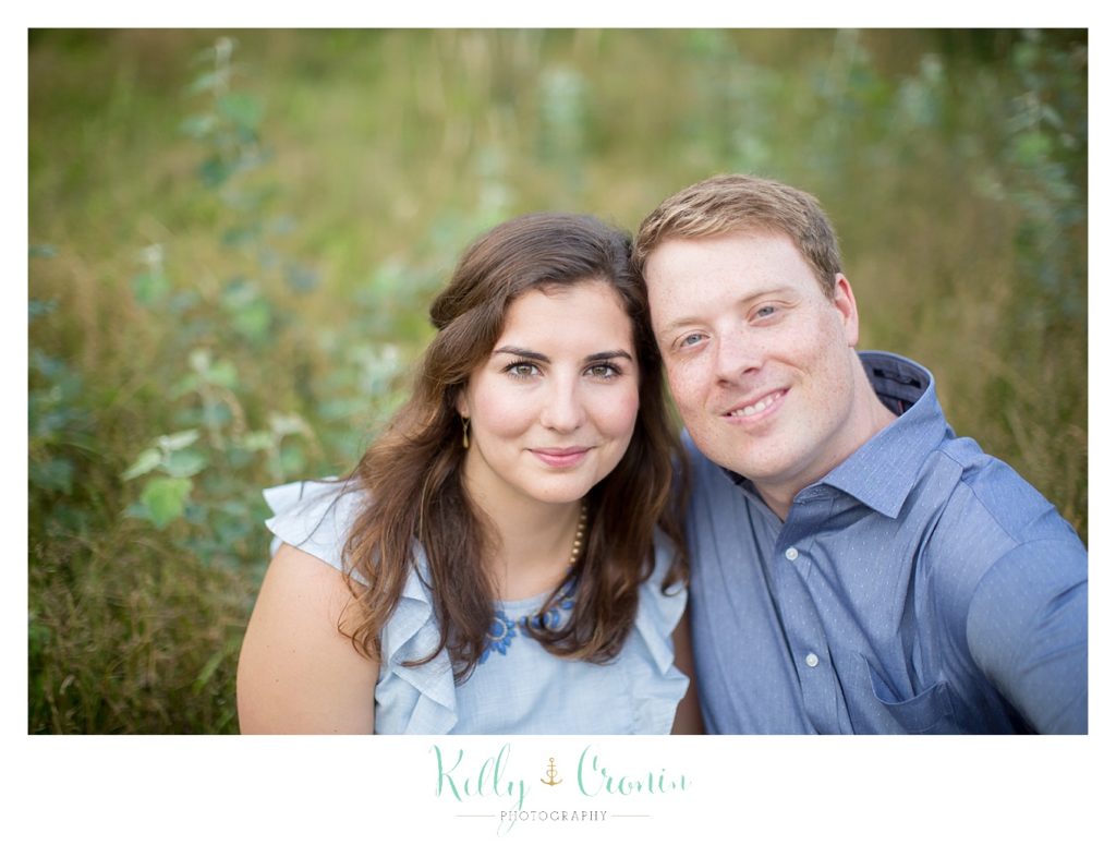 An engaged couple smile for the camera. 