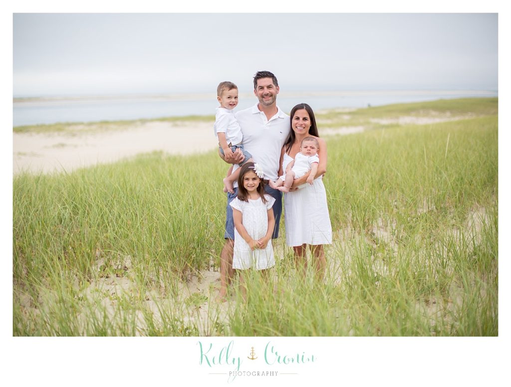 A family stands in the grass  | Kelly Cronin Photography | Seaside Session in Cape Cod