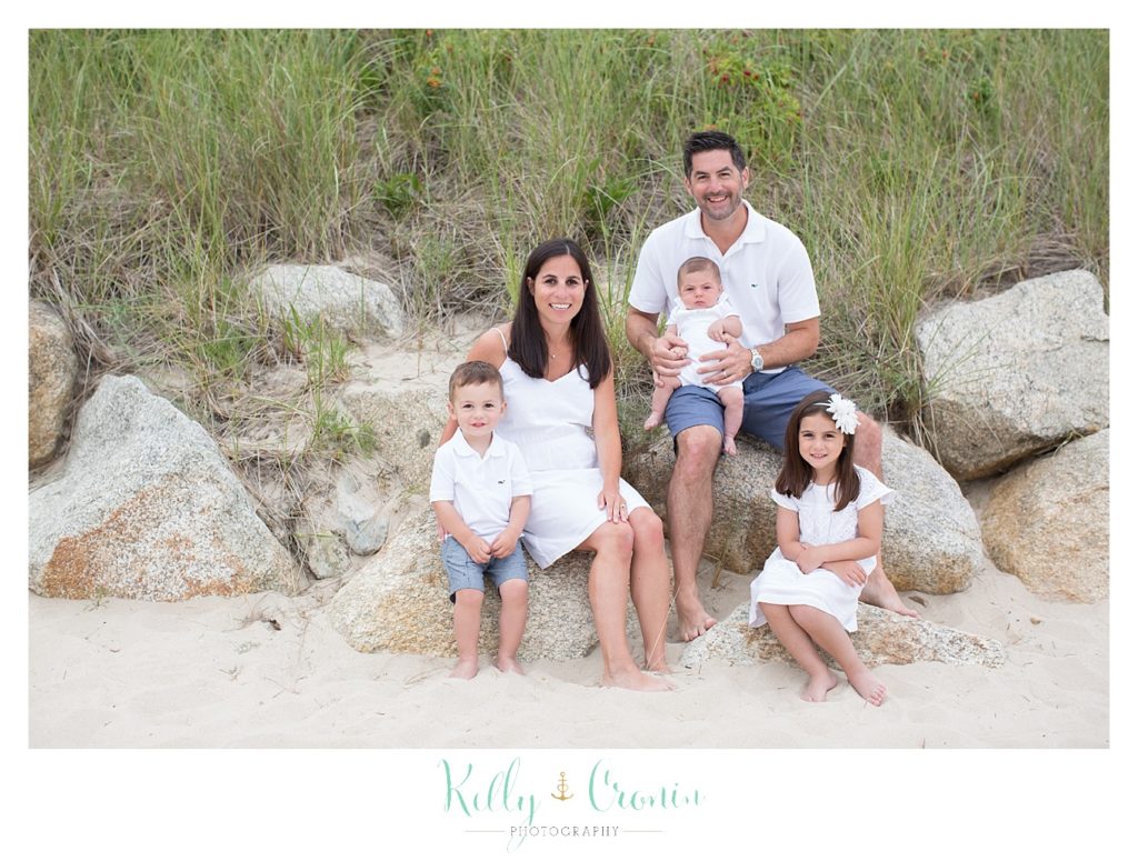 A family poses on rocks  | Kelly Cronin Photography | Seaside Session in Cape Cod