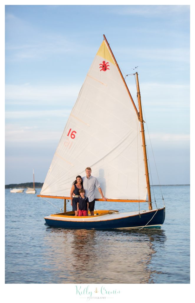 A family stands on a sail boat, posing for their Cape Cod family photographer. 