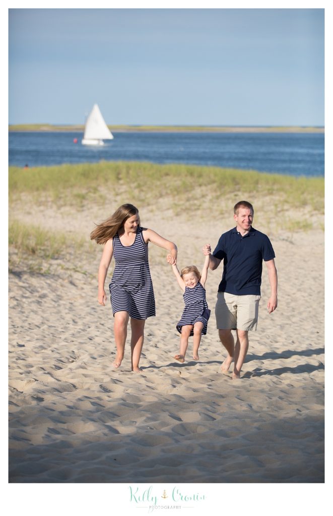 A couple swing their daughter | Kelly Cronin Photography | Family Photography in Cape Cod