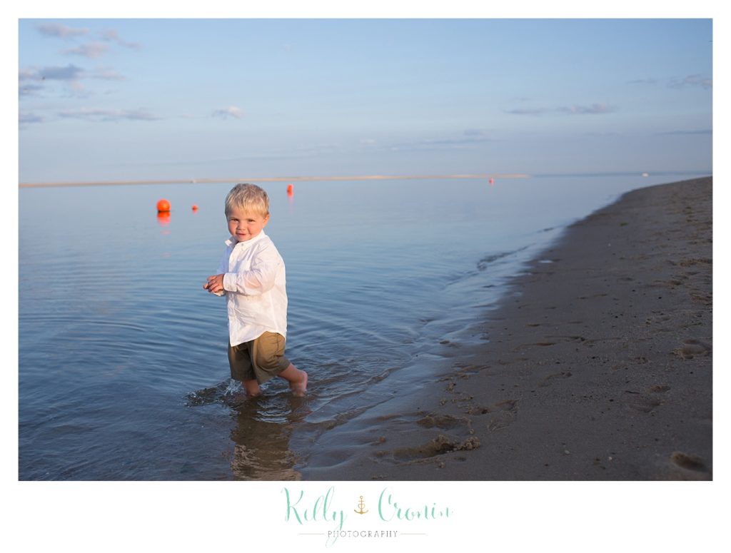 The best family photographer in Cape Cod captures a boy splashing in water. 