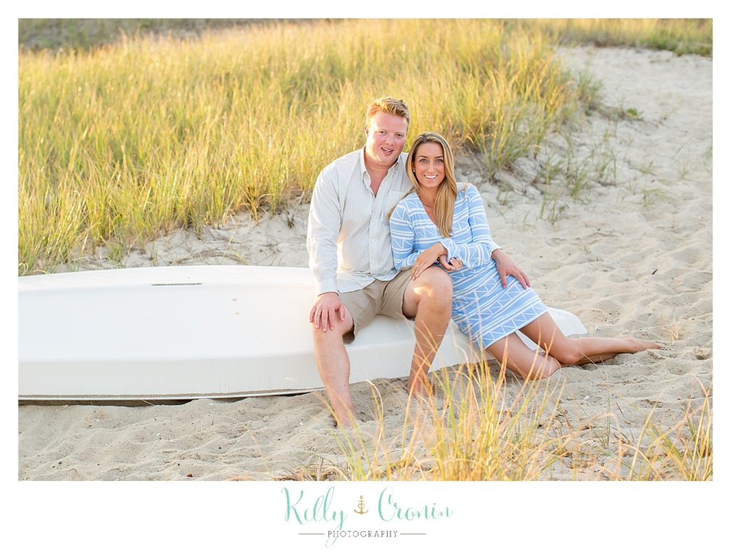 An engaged couple sit on a boat on Hardings Beach. 