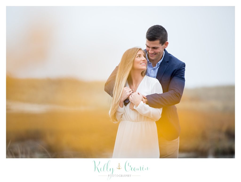 A man holds his fiance, captured by a photographer who specializes in Engagement Photography In Cape Cod. 