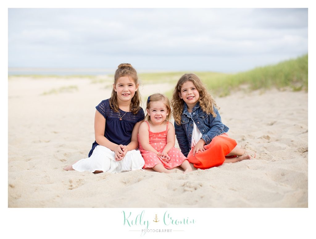 Three sisters sit together for their family photography session. 