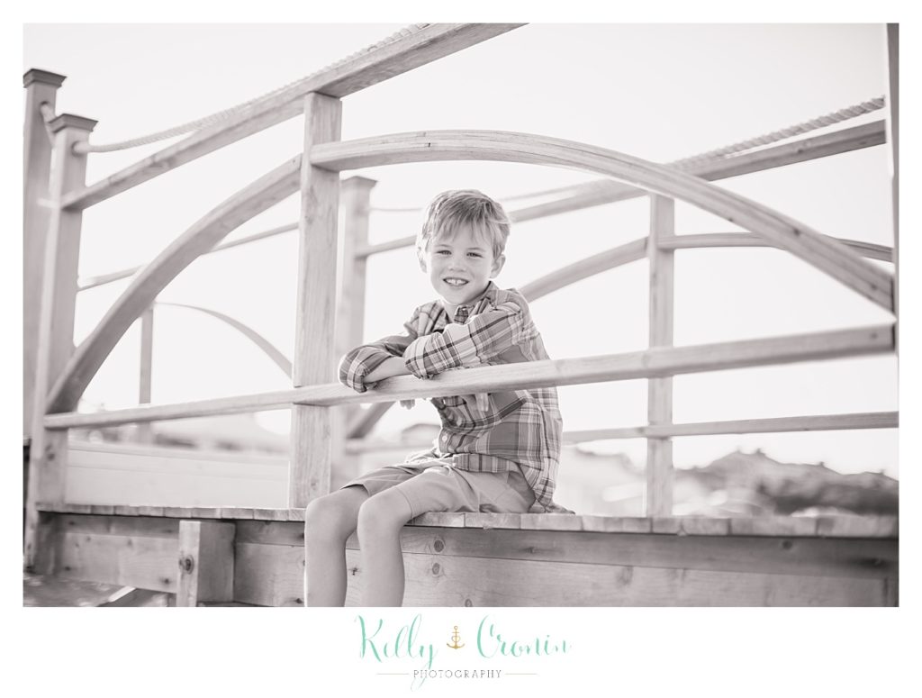 A little boy sits on a bridge. 