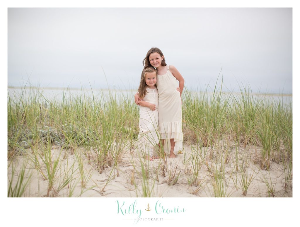 Two sisters in white dresses give each other a hug | Family Photographer In The Cape